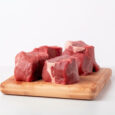 pieces of raw sirloin meat on a chopping board isolated on white background.